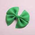 Green textured fabric bow hair clip for children on a soft lavender paper background - Green