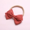 Détail d'un bandeau à nœud en lin rouge brique avec une texture élastique en nylon - Orange Clair