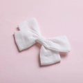 Detail shot of white cotton bow hair clip with textured fabric on pink background - White