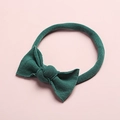 Close-up of dark green nylon baby headband with a cute soft bow detail on pink surface - Dark Green