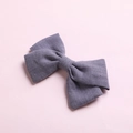Detailed view of gray bamboo cotton bow hair clip with textured weave on a pink background - Gray