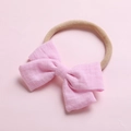Détail d'un bandeau bébé avec un nœud rose texturé sur un ruban de nylon élastique - Rose