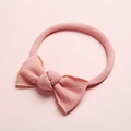 Bandeau bébé en nylon rose doux avec un joli nœud sur un fond pastel assorti - Rose Poudré
