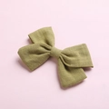Detailed texture of olive green cotton linen bow clip on a soft pink background - Grass Green
