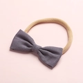 Dettaglio fascia per neonati con fiocco in lino viola e trama intrecciata su fondo rosa - 7-Purple Gray