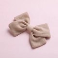 Detail shot of a natural cotton bow hair clip with textured fabric on pink background - Khaki