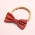 Detail of the rust red linen bow on a soft nude nylon headband for infants and babies - Rust red