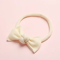 Gros plan du bandeau bébé en nylon crème avec un détail de nœud papillon fait à la main - Poche zippée