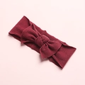 Detail of burgundy ribbed knit baby headband featuring a soft decorative bow design - Burgundy