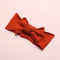 Close-up of rust red soft nylon baby headband with a large handmade bow and ribbed texture - Orange Red