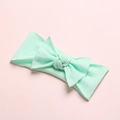 Detailed close-up of soft mint green nylon baby headband with button knot bow - Light Green
