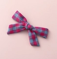 Detailed close-up of a pink and blue plaid fabric bow hair clip on a soft pink surface - Pink Blue Plaid (#3)