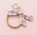 Detail of baby hair tie featuring a pink checkered fabric bow on a soft cream elastic band - US Size 9