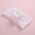 Baby white cable knit headband featuring a soft donut style knot on a pink background - White