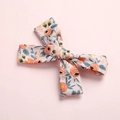 Detaillierte Nahaufnahme der Haarspange mit floralem Stoffbogen und rosa Blumenmuster - Stil 1 Orangefarbene Blume