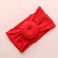 Red cable-knit baby headband with a large decorative donut knot on a pink background - Red