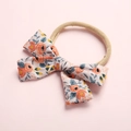 Detailed close-up of a floral bow headband with orange flowers on a soft pink background - Style 1 Orange Floral
