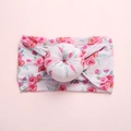 Detailaufnahme eines weichen Nylon-Babystirnbands mit Blumenmuster und Donut-Knoten - Weißer Hintergrund Rosa Blumen