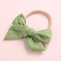 Close-up of sage green ribbed knit baby headband with elastic nylon band detail - Dark Green