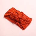 Gros plan d'un bandeau en nylon rouge à pois blancs avec un design à nœud torsadé - Rouge Orangé
