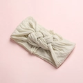 Vue détaillée d'un bandeau pour bébé en tricot blanc crème avec un design à nœud torsadé - Blanc Cassé