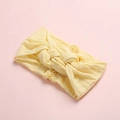 Gros plan du bandeau bébé jaune clair avec nœud sur un fond rose doux - Beige