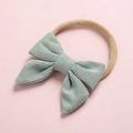 Close-up of baby corduroy bow headband with soft nylon elastic band in sage green - Bean Green (12)