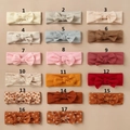 Flat lay detail showing 17 assorted baby bow headbands with floral and rainbow patterns - Random Color Style