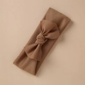 Detail shot of a tan stretch knit baby headband with a handmade bow on a beige background - Brown Style (6)