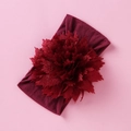 Detailansicht eines dunkelroten Nylon-Blumen-Stirnbands für Babys auf rosa Hintergrund - Burgunderrot
