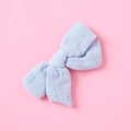 Dettaglio ravvicinato del fiocco in mussola azzurro su uno sfondo rosa confetto - Celeste