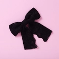 Vue détaillée d'un nœud en dentelle noire avec rubans sur un fond rose pastel - Nœud en Dentelle Noir (18)