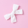 Close-up of a white jacquard cotton bow hair clip with textured stripes on pink background - White