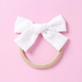 Detailed close-up of soft white jacquard bow with textured fabric on a nude baby headband - White
