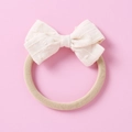 Close-up of the cream Swiss Dot jacquard bow and soft nylon headband for infants - Light Yellow
