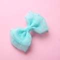 Détail d'une pince à cheveux en tulle bleu clair à pois sur fond rose doux - Vert clair