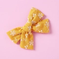 Dettaglio del fiocco in cotone giallo fatto a mano con ricami floreali bianchi e texture - Giallo