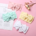Flat lay of soft nylon baby headbands with large bows in pink, green, yellow, and white - Multicolor