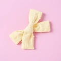 Detail of light yellow bow hair clip with textured polka dots and striped fabric - Yellow