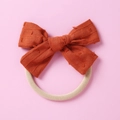 Nahaufnahme der rostorangen Jacquard-Schleife mit weichem Nylon-Haarband für Babys - Orangerot