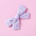 Dettaglio di un fiocco per capelli in cotone viola con delicati ricami floreali bianchi - Lavanda