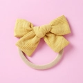 Vue détaillée d'un chouchou nœud jaune avec motif gaufre sur un fond rose pastel - Jaune