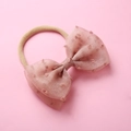 Détail d'un bandeau bébé en nylon doux avec nœud en tulle à pois de couleur rose poudré - Chair