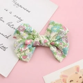 Detail of floral cotton bow hair clip for toddlers on a soft pink decorative background - Green Ditsy Floral