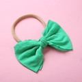 Détail du nœud en tricot vert émeraude sur bandeau bébé en nylon beige doux sur fond rose - Vert Néon