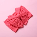 Close-up of soft coral pink nylon baby headband with a large decorative double bow - Watermelon Red