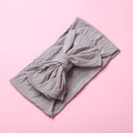 Detail view of soft nylon baby headband with a large dusty purple bow tie on pink background - Gray