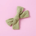 Close-up of baby hair clip featuring avocado green jacquard bow with raised polka dot textures - Green