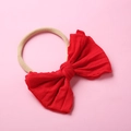 Gros plan d'un bandeau en nylon rouge doux avec grand nœud pour accessoires cheveux bébé - Rouge