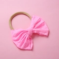 Détail du bandeau en nylon souple avec grand nœud montrant la texture du tissu élastique - Rose Néon